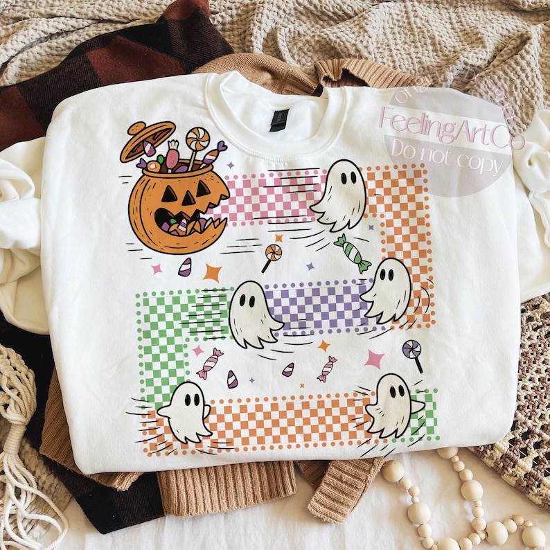 May include: White sweatshirt with a Halloween-themed graphic. The design features a jack-o'-lantern filled with candy, cartoon ghosts, and colorful candy. The words "FeelingArtCo Do not copy" are in the top right corner.