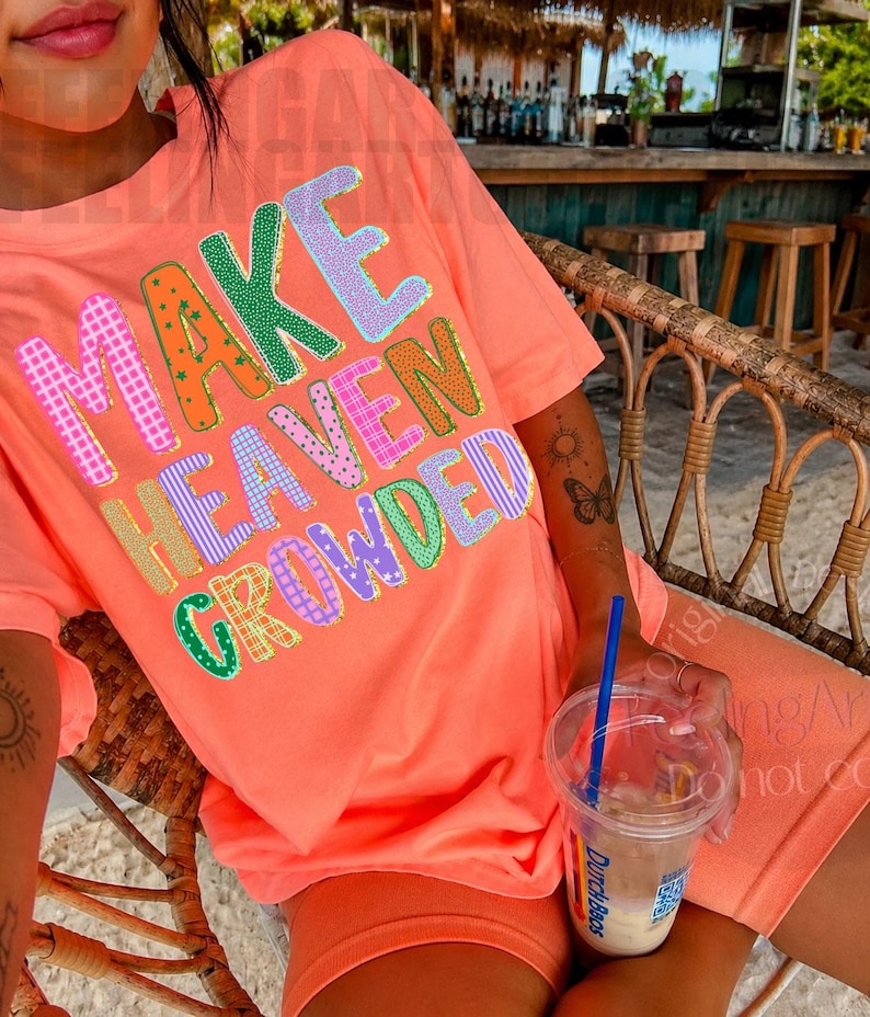 K&ouml;nnte beinhalten: Korallfarbenes T-Shirt und Shorts-Set mit dem Schriftzug "MAKE HEAVEN CROWDED" in bunten, gemusterten Buchstaben. Die Person sitzt in einem Korbstuhl und h&auml;lt ein Getr&auml;nk mit einem blauen Strohhalm.