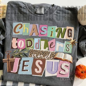 Pu&ograve; includere: T-shirt grigio Comfort Colors con la scritta "Chasing Toddlers and Jesus" in stile collage. Il design include una croce, un libro aperto, una stella e una sezione con stampa leopardata. La maglietta &egrave; taglia XL.