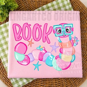 May include: A light pink fabric square featuring the word BOOK in large pink letters. A colorful cartoon worm with teal glasses, pink, blue, and yellow segments, and small floral accents is illustrated alongside orange, purple, and teal star shapes.