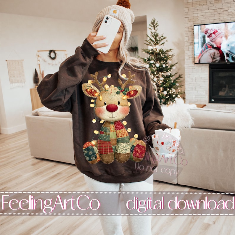 Puede incluir: Una sudadera marr&oacute;n con un dise&ntilde;o de reno navide&ntilde;o. El reno tiene una nariz roja, cuernos y luces de cadena. Lleva una bufanda de retazos y tiene una cara sonriente. El texto "FeelingArtCo digital download" est&aacute; en la parte inferior.