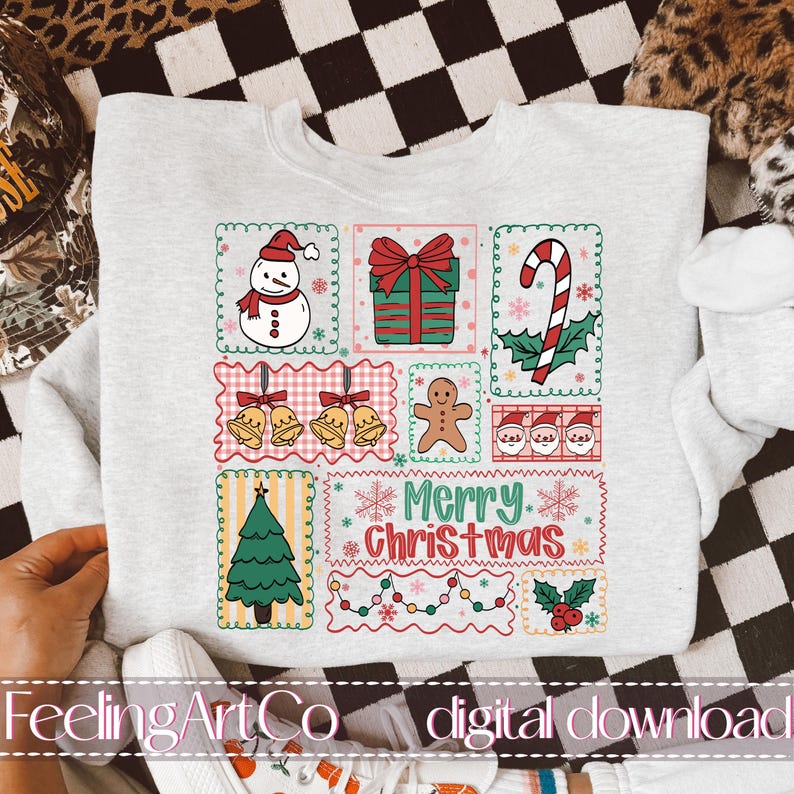 May include: Light gray sweatshirt with a colorful Christmas-themed design. The design includes a snowman, wrapped gift, candy cane, bells, gingerbread man, Santa faces, Christmas tree, and the text "Merry Christmas."