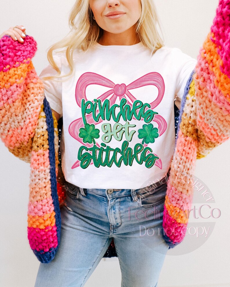 May include: White t-shirt with a pink bow and the text "Pinches get stitches" in green. The shirt is paired with light blue jeans and a colorful, chunky knit cardigan in shades of pink, orange, yellow, and blue.
