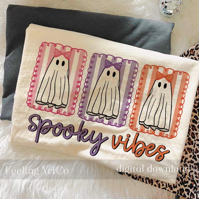 May include: Off-white t-shirt featuring three cartoon ghosts with bows in pink, purple, and orange frames. The shirt has the words "Spooky Vibes" in purple and orange. The shirt is a digital download.