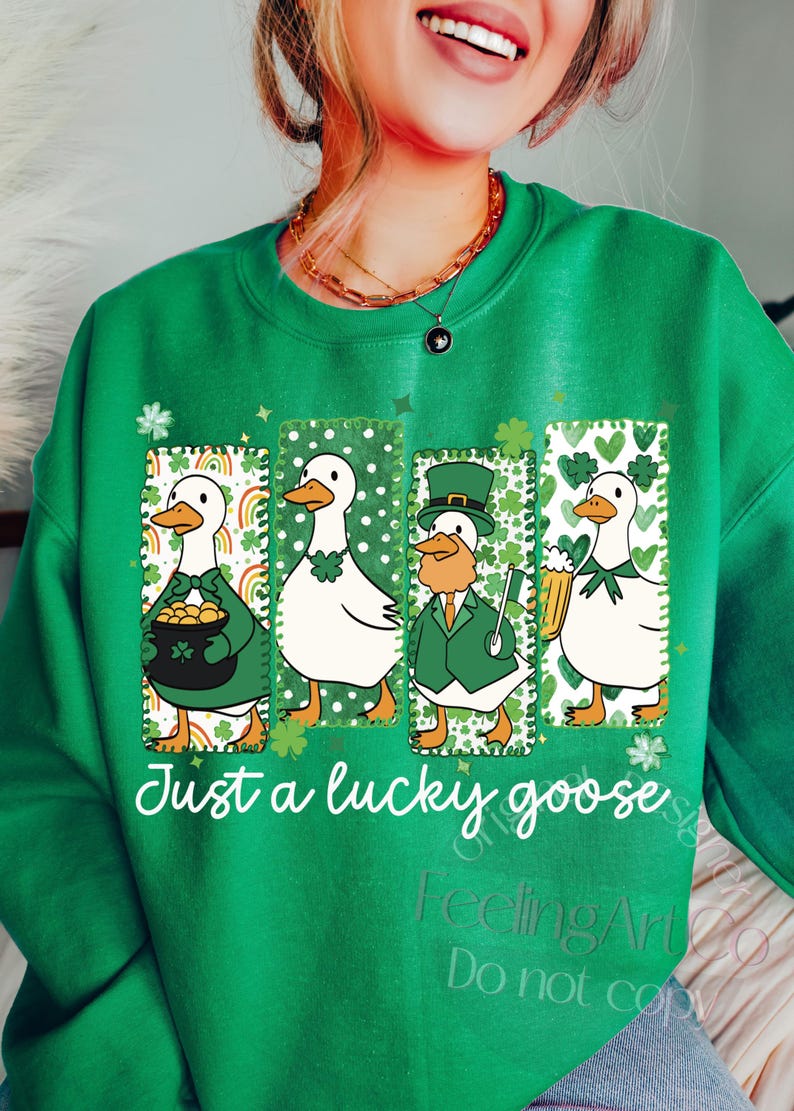 May include: Green sweatshirt with a St. Patrick's Day theme. Features four cartoon geese in rectangular frames, each with a different design, including rainbows, shamrocks, and a leprechaun. The text "Just a lucky goose" is printed below the images.