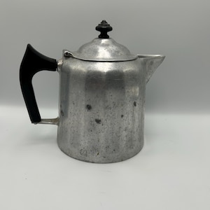 May include: A silver aluminum coffee pot with a black plastic handle and knob on the lid.