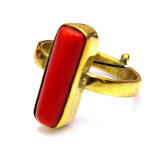 Pode incluir: Um anel de ouro com uma pedra de coral vermelho em forma retangular.
