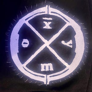 Könnte beinhalten: Ein weißer Kreis mit einem schwarzen X darin. Das X ist in vier Quadranten unterteilt, jeder mit einem Buchstaben: O, X, I und M.