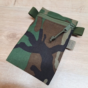 May include: A camouflage green zippered pouch with a black strap and a green pull cord. The pouch has a label that reads "Resilient Equipment".