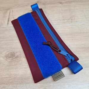 Pochette pour passeport bordeaux avec fermeture éclair bleue et empiècement bleu