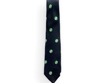 May include: A navy blue tie with a repeating pattern of light green polka dots. The tie is made of a smooth fabric and is displayed against a white background. The tie is a classic accessory.