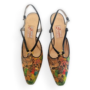 Peut inclure: Une paire de chaussures à talons marrons et noires avec un imprimé floral et des accents dorés. Les chaussures ont une bride à la cheville et une fermeture à boucle. Les chaussures sont fabriquées par Scarpini, Made in Italy.