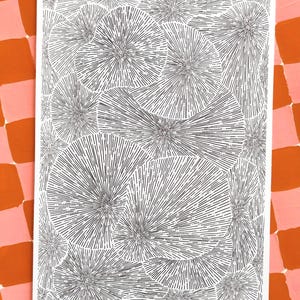 May include: Monochrome abstract art print with a pattern of radiating circles. The artwork is on a white background, with a pink and orange checkered background. Signed "ber bale 2025".