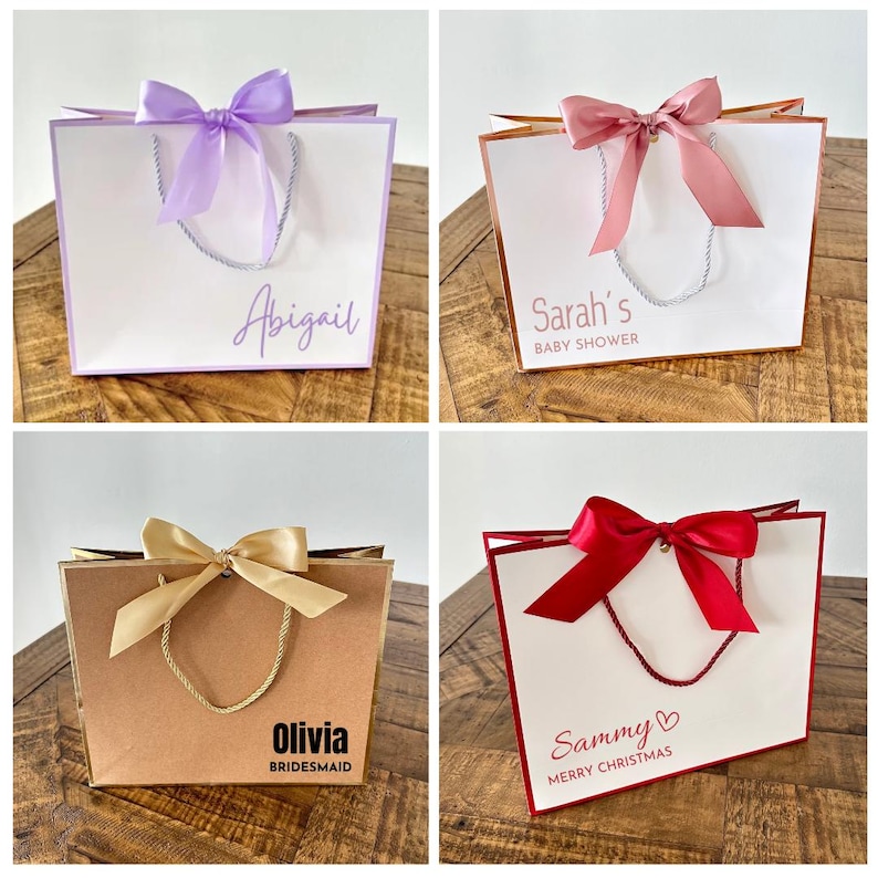 Pode incluir: Quatro sacos de presente com fitas de diferentes cores e mensagens personalizadas. Os sacos s&atilde;o brancos, castanhos e creme com guarni&ccedil;&otilde;es douradas e vermelhas. As mensagens nos sacos s&atilde;o "Abigail", "Ch&aacute; de Beb&ecirc; da Sarah", "Olivia Madrinha" e "Sammy Feliz Natal".