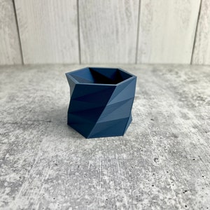 May include: A dark blue geometric planter with a hexagonal shape. The planter is made of a smooth, textured material.