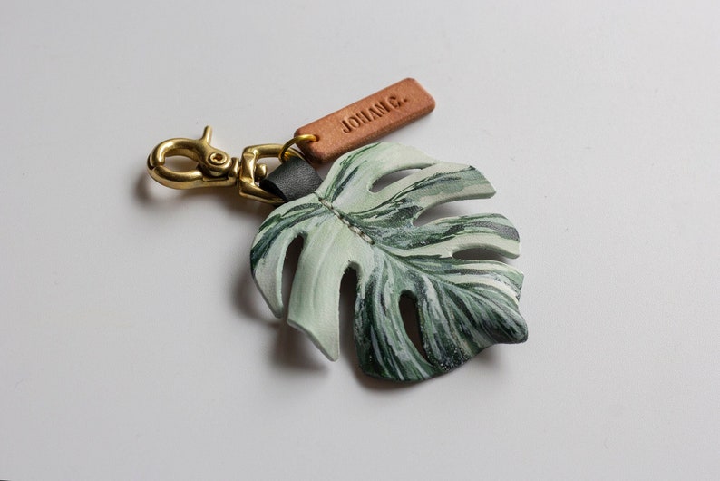 Monstera Deliciosa var Borsigiana 'Albo' Brokig läderväskeberlock, schweizerostväxtnyckelring, väsktillbehör med glänsande mässingsspänne bild 1