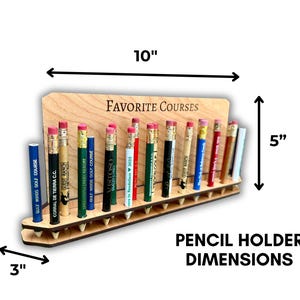 May include: A wooden pencil holder with the text "FAVORITE COURSES" engraved on the front. The holder is 10 inches wide, 5 inches tall, and 3 inches deep. It has 18 slots for pencils, each with a different golf course name printed on it.