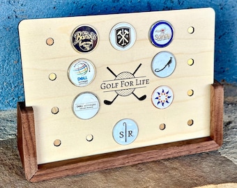 May include: A wooden golf ball display stand with a walnut base. The stand has 10 holes for displaying golf balls. The stand has the text "GOLF FOR LIFE" printed on it.