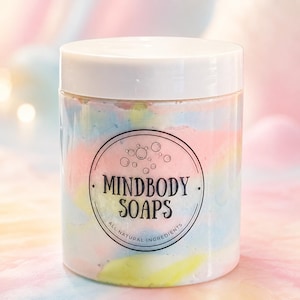 May include: A clear plastic jar with a white lid containing a pastel-colored swirl of soap. The label features a circular design with bubbles and the text MINDBODY SOAPS ALL NATURAL INGREDIENTS in black ink centered on the front of the container.