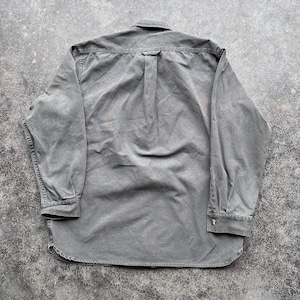 May include: A long-sleeved, button-down shirt in a muted green color. The shirt has a classic collar, buttoned cuffs, and a curved hem. The back of the shirt features a yoke and a box pleat for added comfort and style. The fabric appears to be a soft, washed cotton.