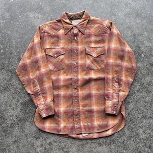 May include: A long-sleeved, button-down shirt in a plaid pattern of orange, red, and brown. The shirt has two chest pockets with pointed flaps and snap closures. The collar and cuffs are a darker shade of brown.