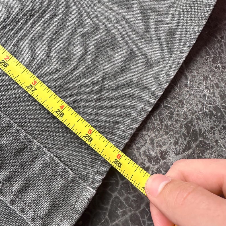 May include: A white ceramic mug with a black handle and the text "But First, Coffee" in a bold, black font. The mug is set against a blurred background, highlighting its clean design.