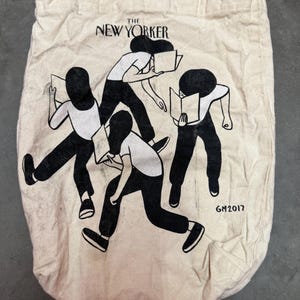 May include: Off-white canvas tote bag featuring the text "The New Yorker" above a black and white illustration of figures reading books. The illustration includes four figures in motion, with the artist's signature "GM2017" at the bottom.