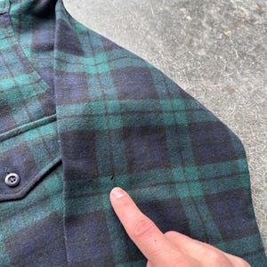 May include: A white ceramic mug with a black handle and the text "But First, Coffee" in a bold, black font. The mug is set against a blurred background, suggesting a cozy setting.