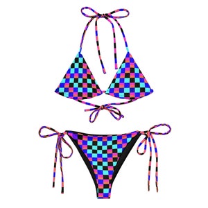 Puede incluir: Un bikini de cuadros negros, rosas y azules con tirantes ajustables. La parte superior es de estilo triangular y la inferior es de estilo atrevido.