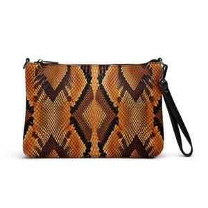 May include: A rectangular clutch with a snakeskin pattern in shades of brown, tan, and black. The clutch has a black wrist strap and a black zipper. The bag is designed to be carried by hand.