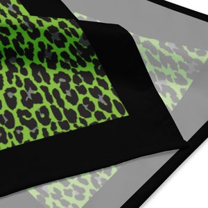 May include: A green and black leopard print fabric with a black border. The fabric is folded in half and the print is visible on both sides.