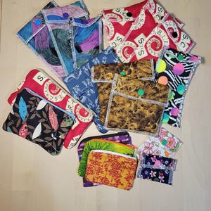 May include: A collection of colorful fabric pouches with various patterns and designs. Some pouches have a zipper closure, while others have a button closure. The pouches are made of different fabrics, including cotton, linen, and silk. The pouches are perfect for storing small items, such as jewelry, coins, or keys.