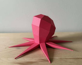 May include: A bright pink papercraft octopus with a geometric head and eight tentacles.