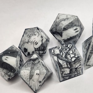 May include: A set of seven polyhedral dice made of clear resin, each featuring intricate black and white illustrations of ghosts, gnarled trees, and dark forest scenes embedded within the material. The dice have sharp edges and numbered faces.