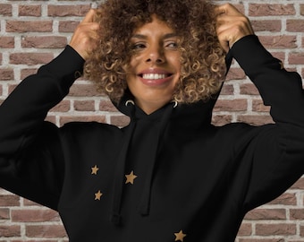 May include: A black hoodie with a gold star pattern. The hoodie has a drawstring hood and a kangaroo pocket.