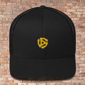 May include: A black mesh trucker hat with a yellow vinyl record logo embroidered on the front.