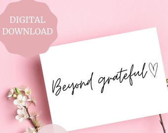 May include: A white card with black calligraphy that reads "Beyond grateful" with a small heart symbol. The card is on a pink background with a white flower branch.