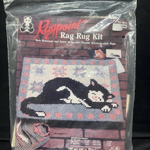 May include: A sealed Rugpoint Rag Rug Kit featuring a black cat design. The kit includes instructions to turn fabric strips into heirloom-style rugs. The packaging displays a finished rug with a cat on a blue background.