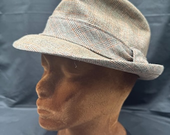 Könnte beinhalten: Ein brauner und grauer karierter Fedora-Hut mit einem braunen Band.