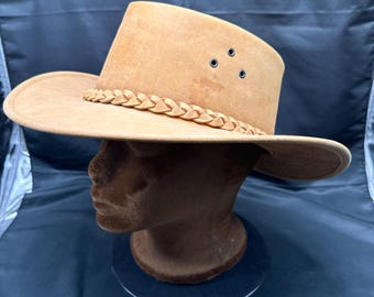 May include: A brown leather cowboy hat with a braided leather band and three eyelets on the crown.