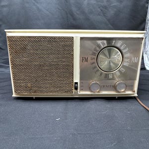 May include: A vintage Zenith AM/FM radio in off-white with a silver face and a dial that reads "FM" and "AM".