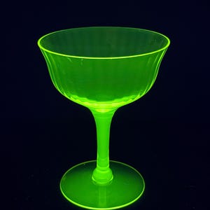 Può includere: Un calice di vetro verde brillante con una coppa scanalata e un gambo alto. Il calice è in vetro all'uranio, che brilla sotto una luce nera.