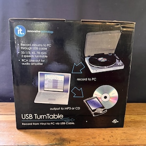 May include: Black box with a USB Turntable. The box shows a turntable, laptop, CD, and MP3 player. Text on the box reads "Record Albums to PC through USB cable" and "Record from Vinyl to PC via USB Cable."