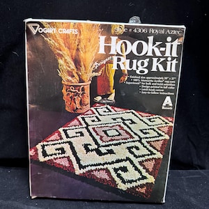 May include: A Vogart Crafts Hook-it Rug Kit, style #4306 Royal Aztec. The box features a finished rug with a geometric pattern in red, white, and black, and text including 'Finished size approximately 20" x 27"' and '100% Monsanto Acrilan rug yarn'.