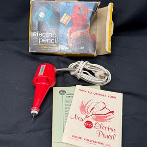 May include: A red electric pencil with a white cord and instructions on how to operate it. The box says "electric pencil" and "makes permanent engravings, markings, designs on wood and leather".