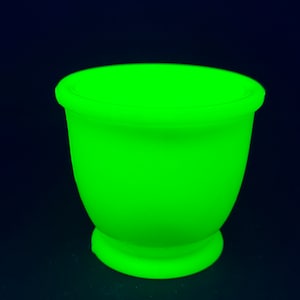 Puede incluir: Un huevero de cerámica verde brillante y fluorescente.