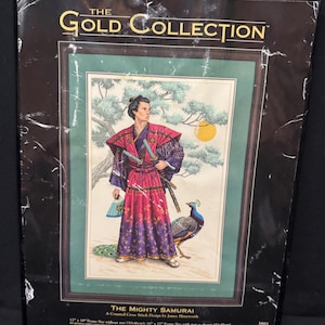 Puede incluir: Un kit de punto de cruz contado titulado The Mighty Samurai de The Gold Collection. El empaque presenta una ilustración de un samurái con una túnica roja y morada con dos espadas, un pavo real y un pino. El kit incluye tela Aida color marfil de 18 count.