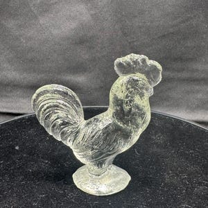 May include: A rustic wooden sign with the text "Welcome" in a handwritten style. The sign is painted white with a distressed finish, and features a decorative floral element in the corner. The background is a blurred image of a wooden surface.