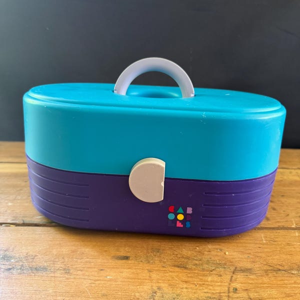 Estuche de maquillaje vintage Caboodles con acabado verde azulado y morado, bandejas cerradas y escalonadas
