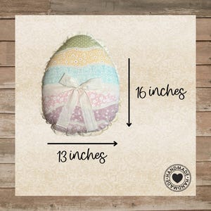 May include: An egg-shaped pillow, approximately 16 inches tall and 13 inches wide, with a pastel color scheme. The pillow features layers of fabric in green, yellow, blue, and pink, with a white bow. The pillow is handmade.